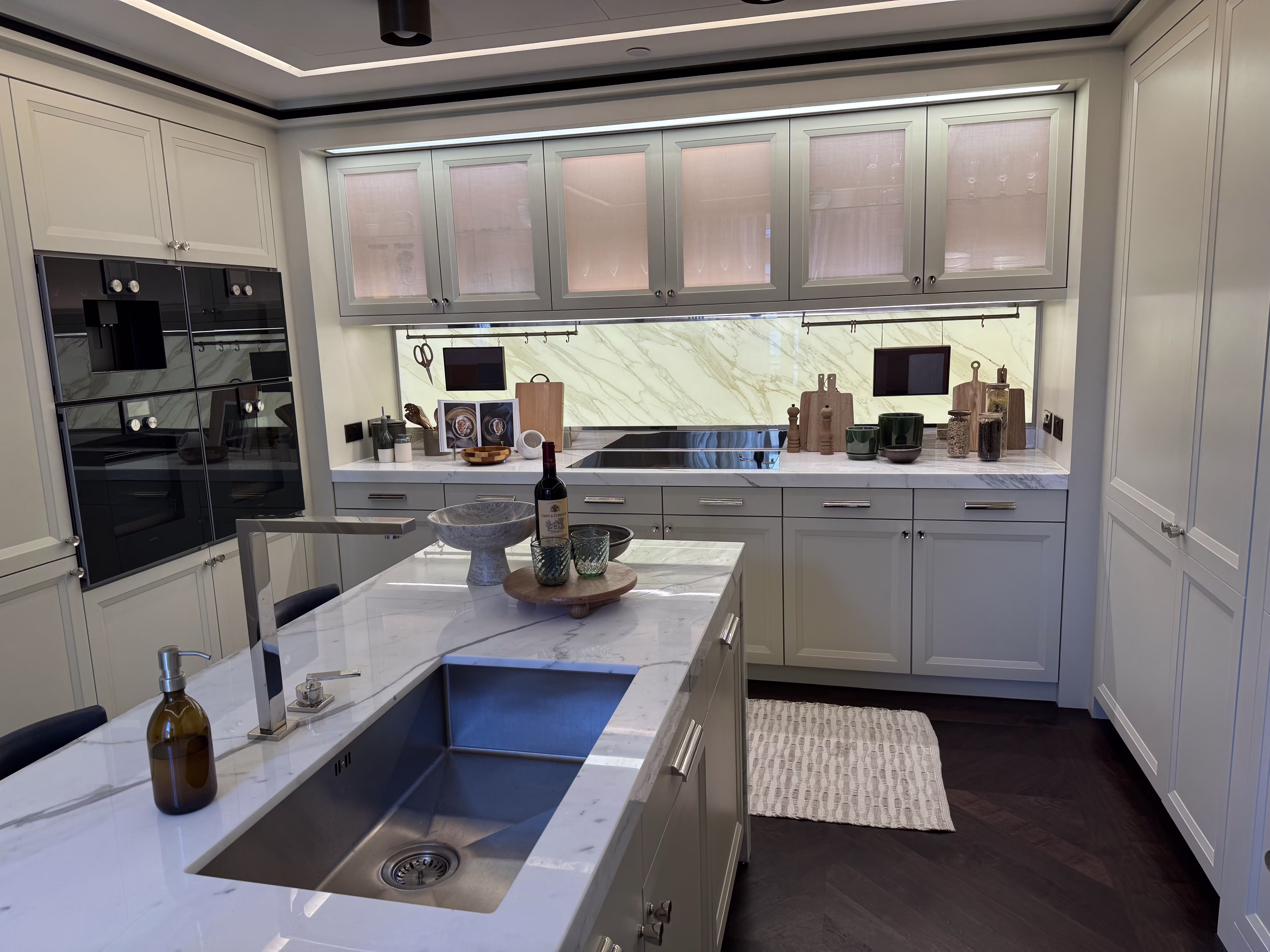 A bright kitchen with a veined stone island, sink and matching worktops